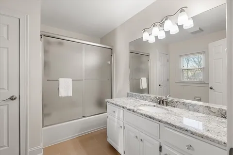 a bathroom with a granite countertop sink a mirror and a bathtub