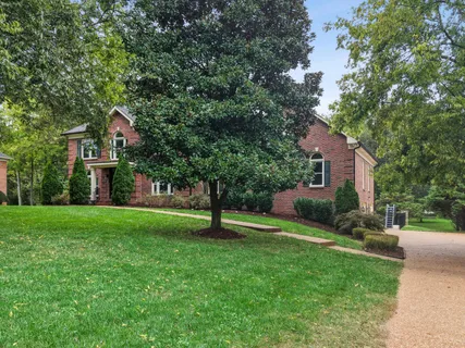 a front view of a house with a yard and tree