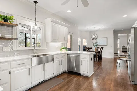 a kitchen with white cabinets sink and chairs