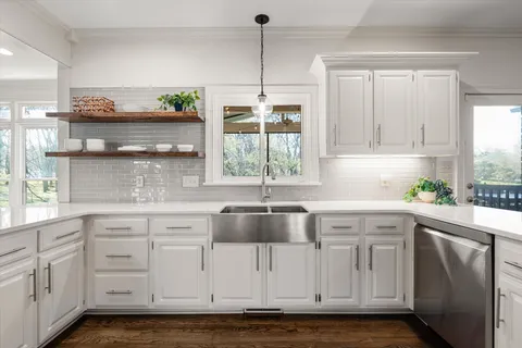 a kitchen with granite countertop a sink window and cabinets