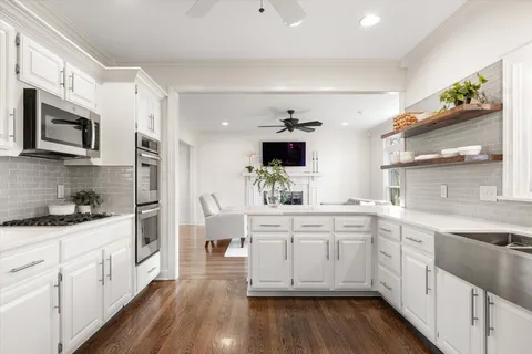 a kitchen with a sink stove cabinets and wooden floor