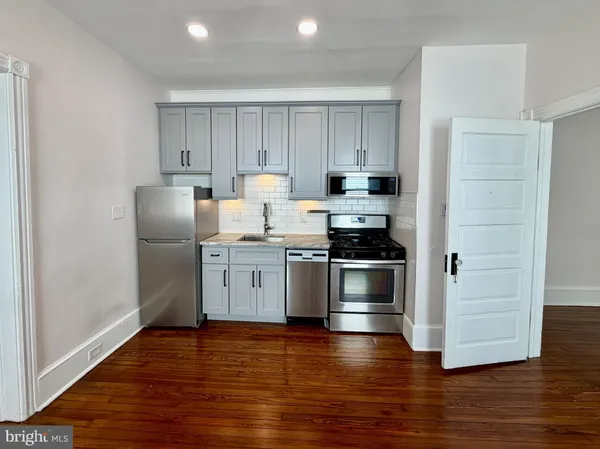 a kitchen with a refrigerator stove and wooden floor