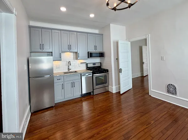 a kitchen with granite countertop a refrigerator and a stove top oven