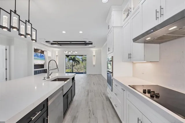 a kitchen with granite countertop a stove a sink a refrigerator and a wooden floor