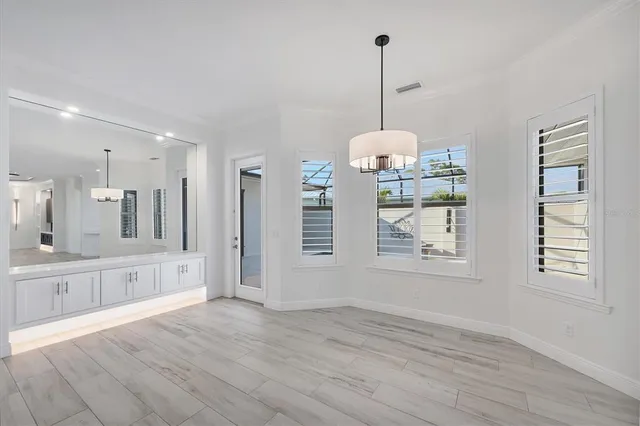a view of an empty room with wooden floor kitchen view and a window