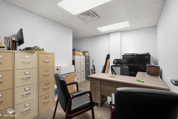 a room with a chair and white cabinets