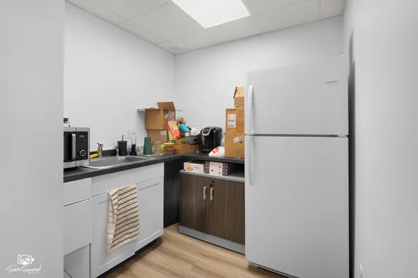a kitchen with a sink a refrigerator and wooden floor