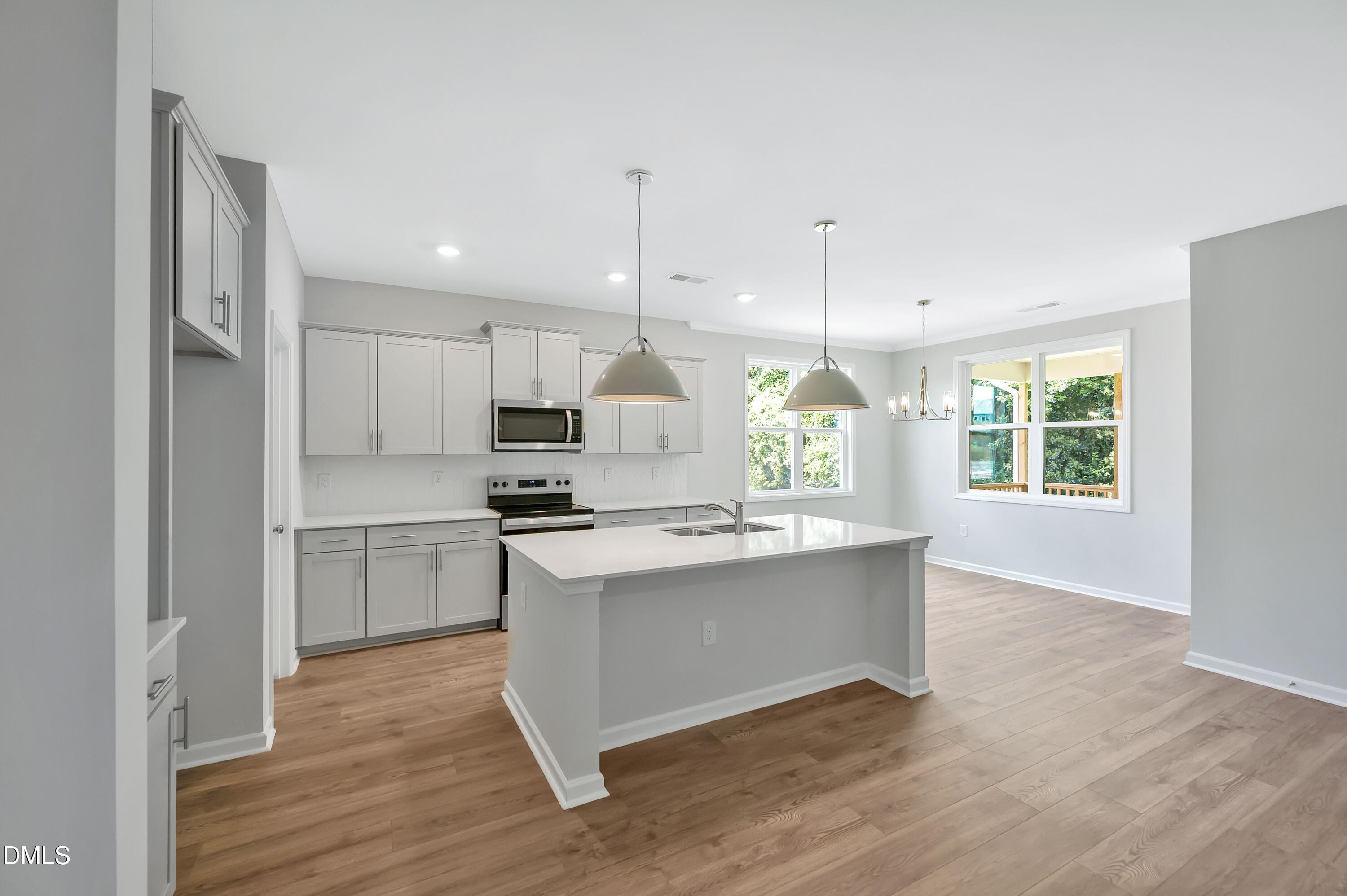 294 White Azalea Way Benson, NC 27504 - Photo 2 of 15 a kitchen with kitchen island a sink a stove a refrigerator and white cabinets