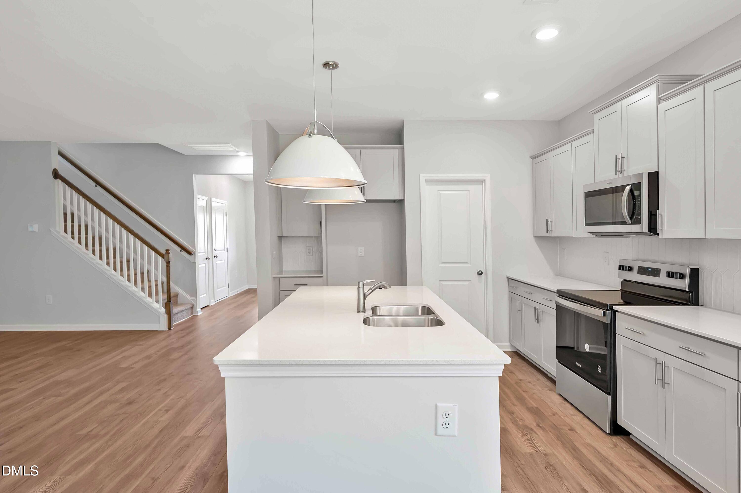 294 White Azalea Way Benson, NC 27504 - Photo 3 of 15 a kitchen with kitchen island a stove a sink and a refrigerator