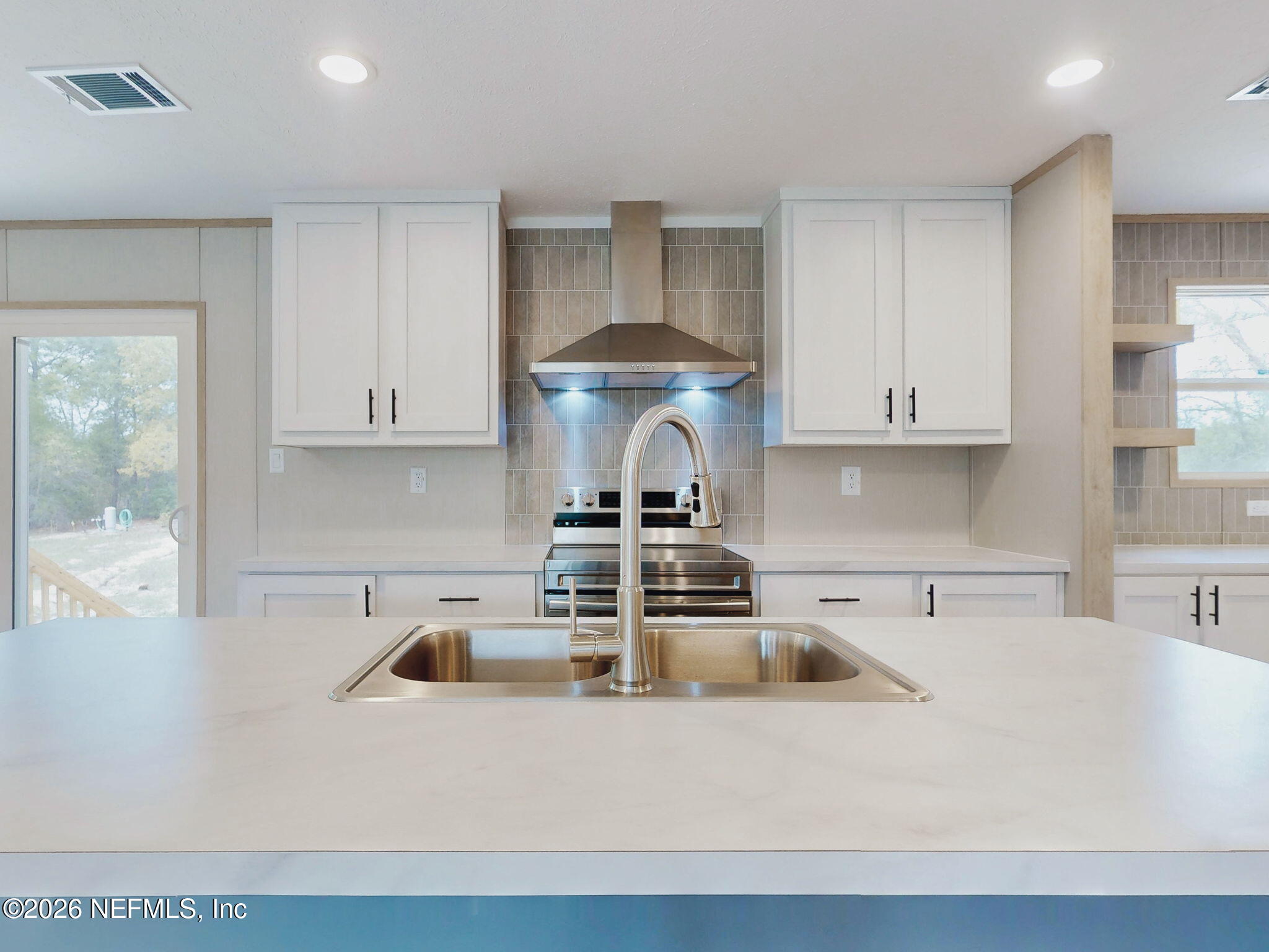 5784 County Road 214 Keystone Heights, FL 32656 - Photo 25 of 62 a kitchen with a stove and white cabinets
