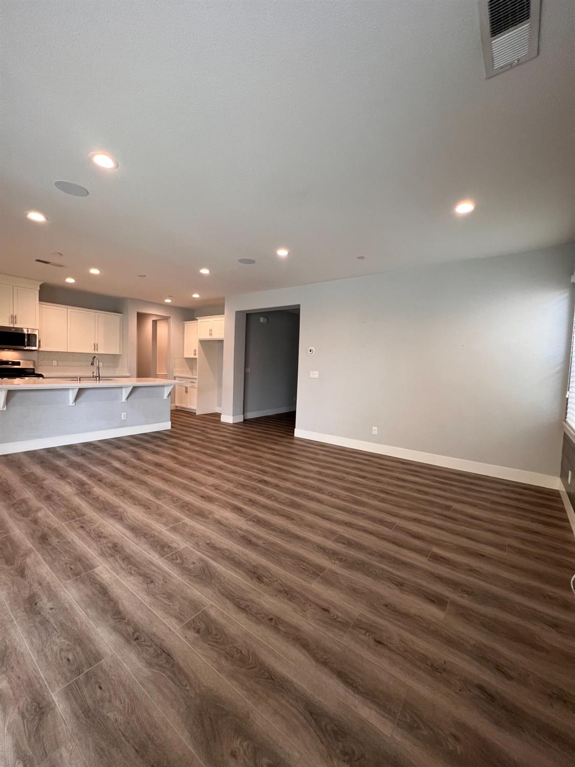 445 Expedition Avenue Madera, CA 93636 - Photo 13 of 36 a view of an empty room with wooden floor and a kitchen
