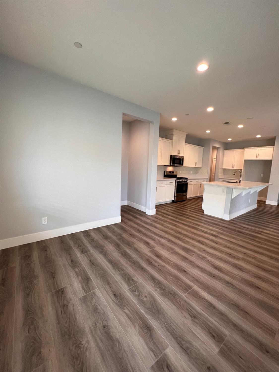 445 Expedition Avenue Madera, CA 93636 - Photo 15 of 36 a view of kitchen and empty room with wooden floor