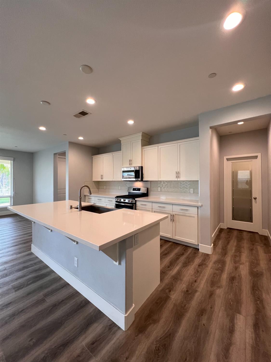 445 Expedition Avenue Madera, CA 93636 - Photo 16 of 36 a large white kitchen with kitchen island sink stove and white cabinets