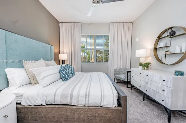 a bedroom with a bed a mirror on dresser and a window