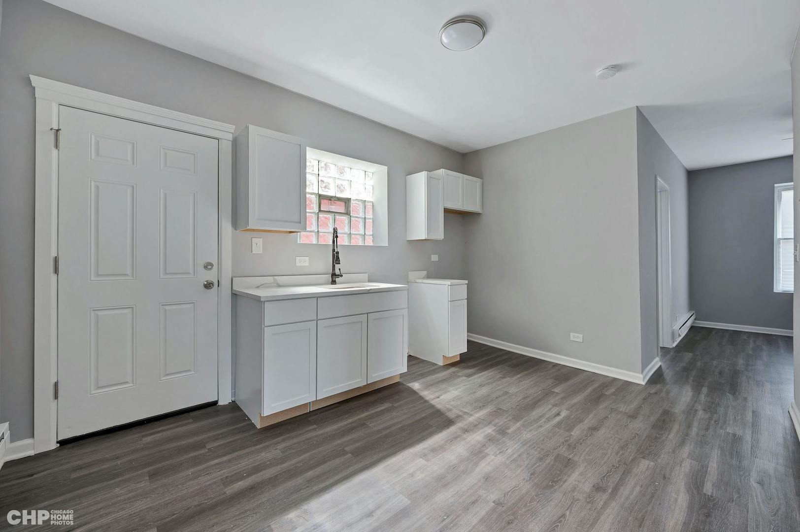 16 East 118th Place, Unit 1F Chicago, IL 60628 - Photo 3 of 10 a view of a kitchen with white cabinets and wooden floor