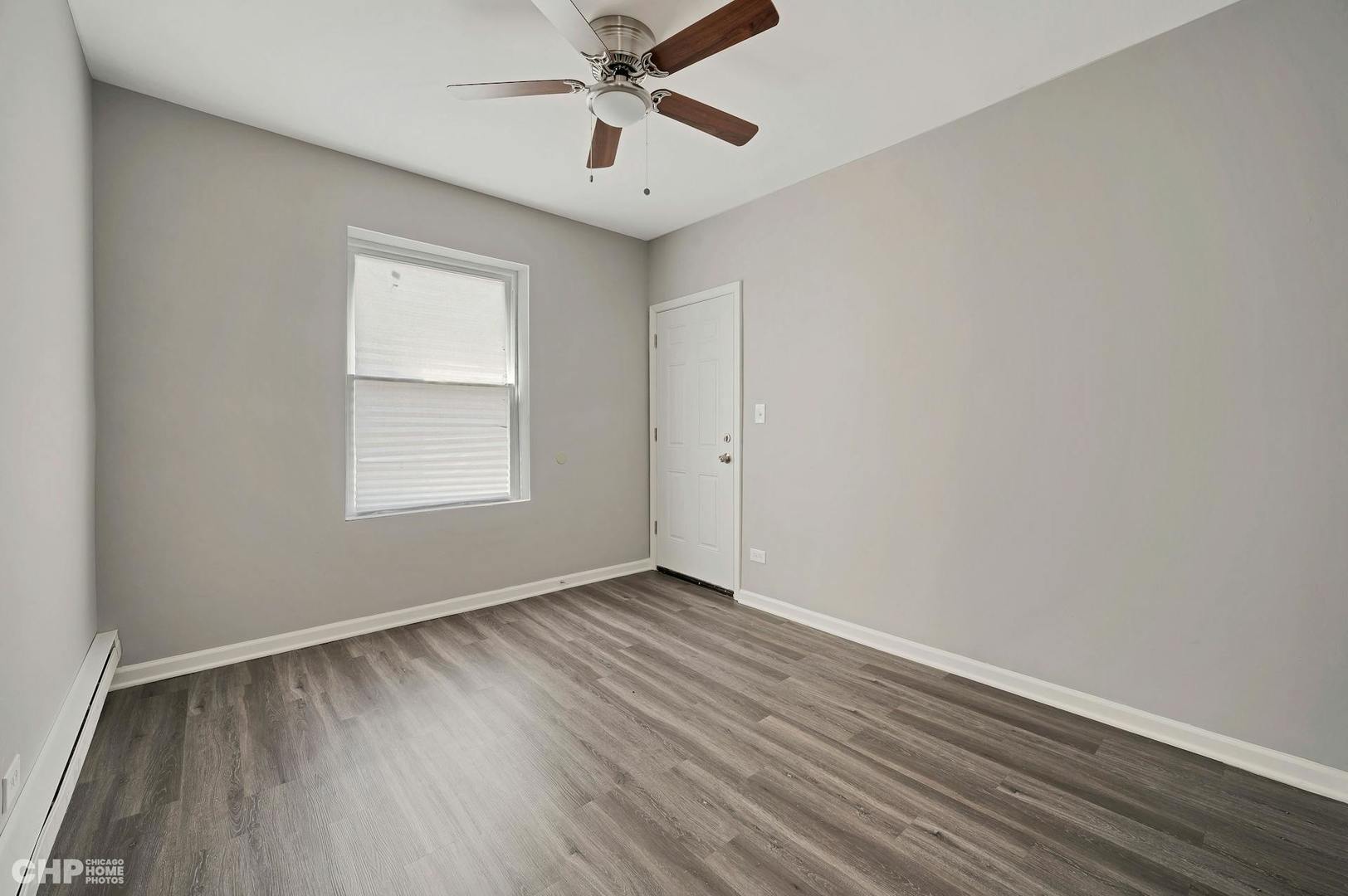 16 East 118th Place, Unit 1F Chicago, IL 60628 - Photo 7 of 10 an empty room with wooden floor chandelier fan and windows