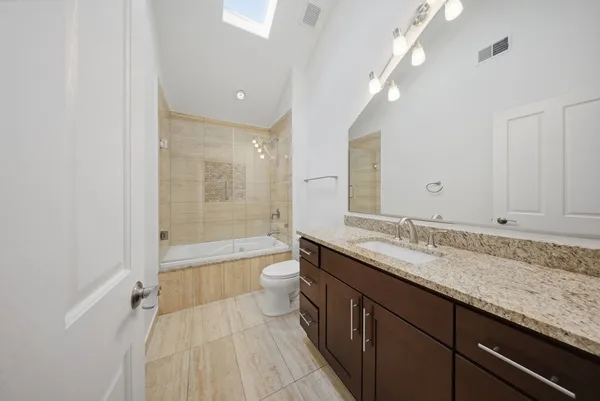 a bathroom with a granite countertop sink mirror toilet and bathtub