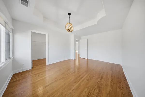 a view of an empty room with wooden floor and window