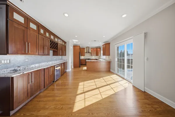 a large space with kitchen island granite countertop wooden floor a large window and a refrigerator
