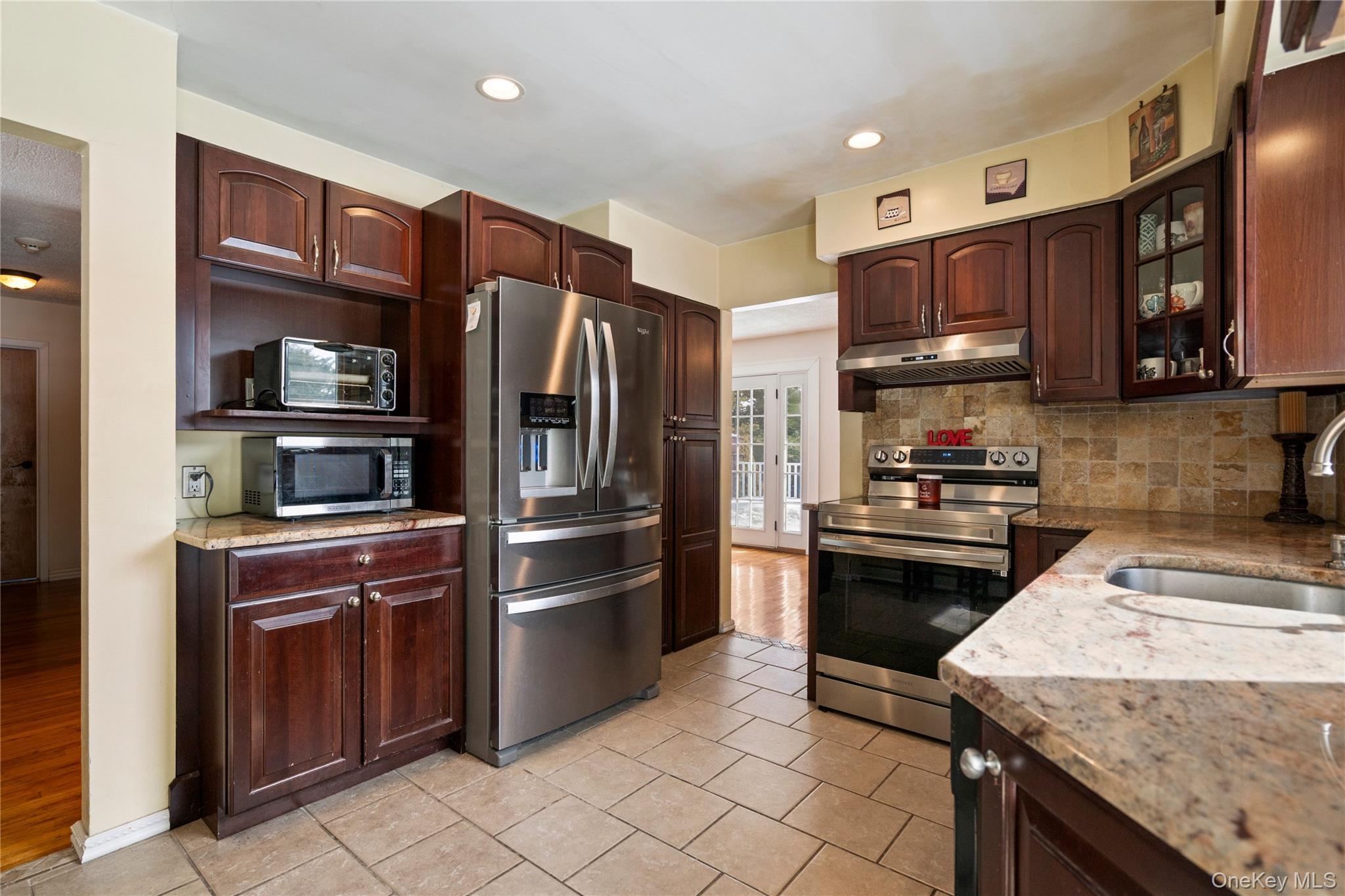 25 State Place Huntington, NY 11743 - Photo 13 of 33 a kitchen with granite countertop stainless steel appliances and wooden cabinets