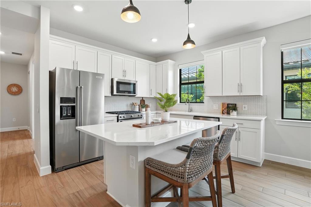 11945 Sacra Place Fort Myers, FL 33913 - Photo 12 of 50 Kitchen featuring appliances with stainless steel finishes, tasteful backsplash, white cabinets, a kitchen island, and recessed lighting
