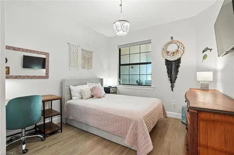 a bedroom with a bed a window and a flat screen tv