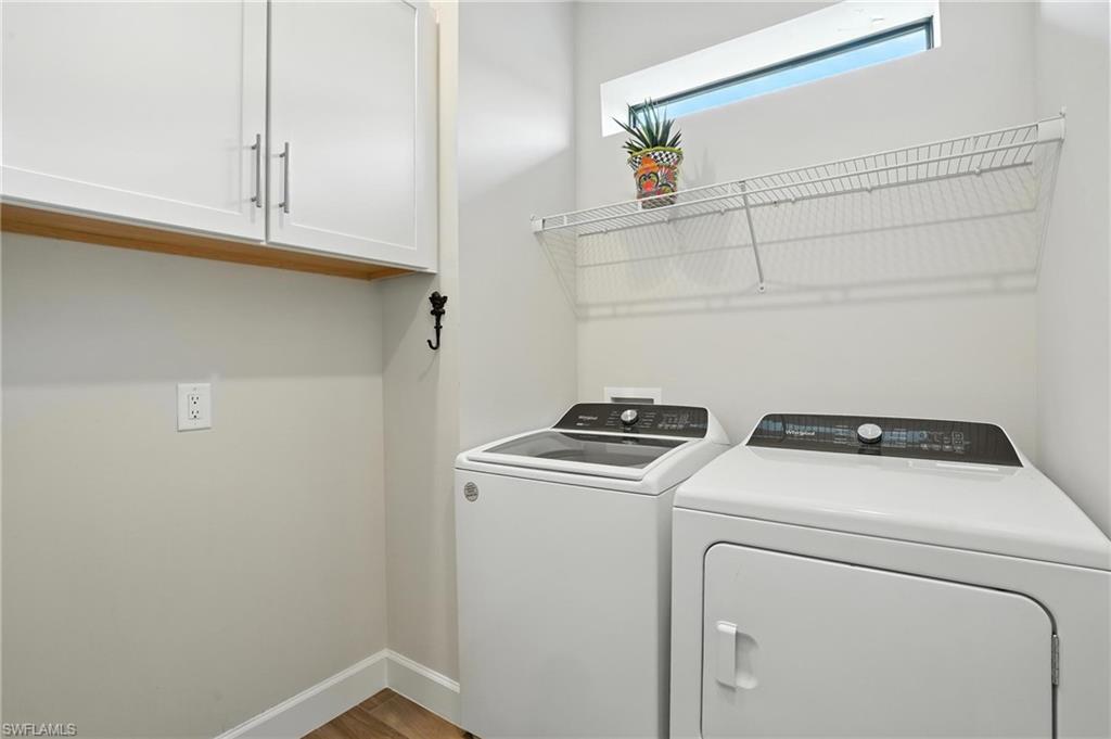 11945 Sacra Place Fort Myers, FL 33913 - Photo 29 of 50 Laundry room with washer and dryer, cabinet space, and wood finished floors