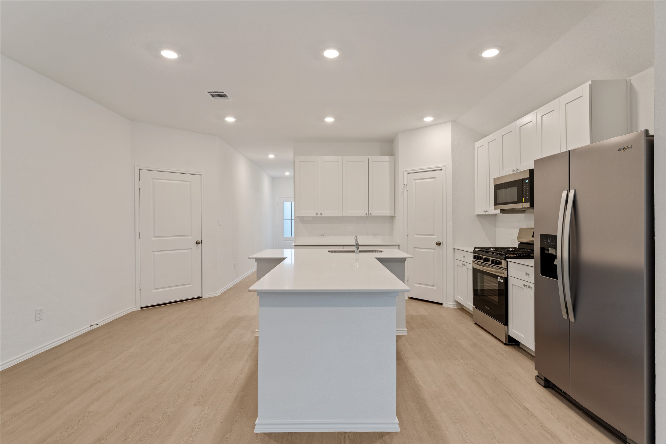 115 Parsons Kyle, TX 78640 - Photo 2 of 18 A pristine kitchen features a large central island, integrated appliances, and light-toned flooring.