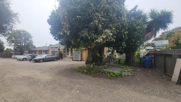a view of a house with a yard and large trees