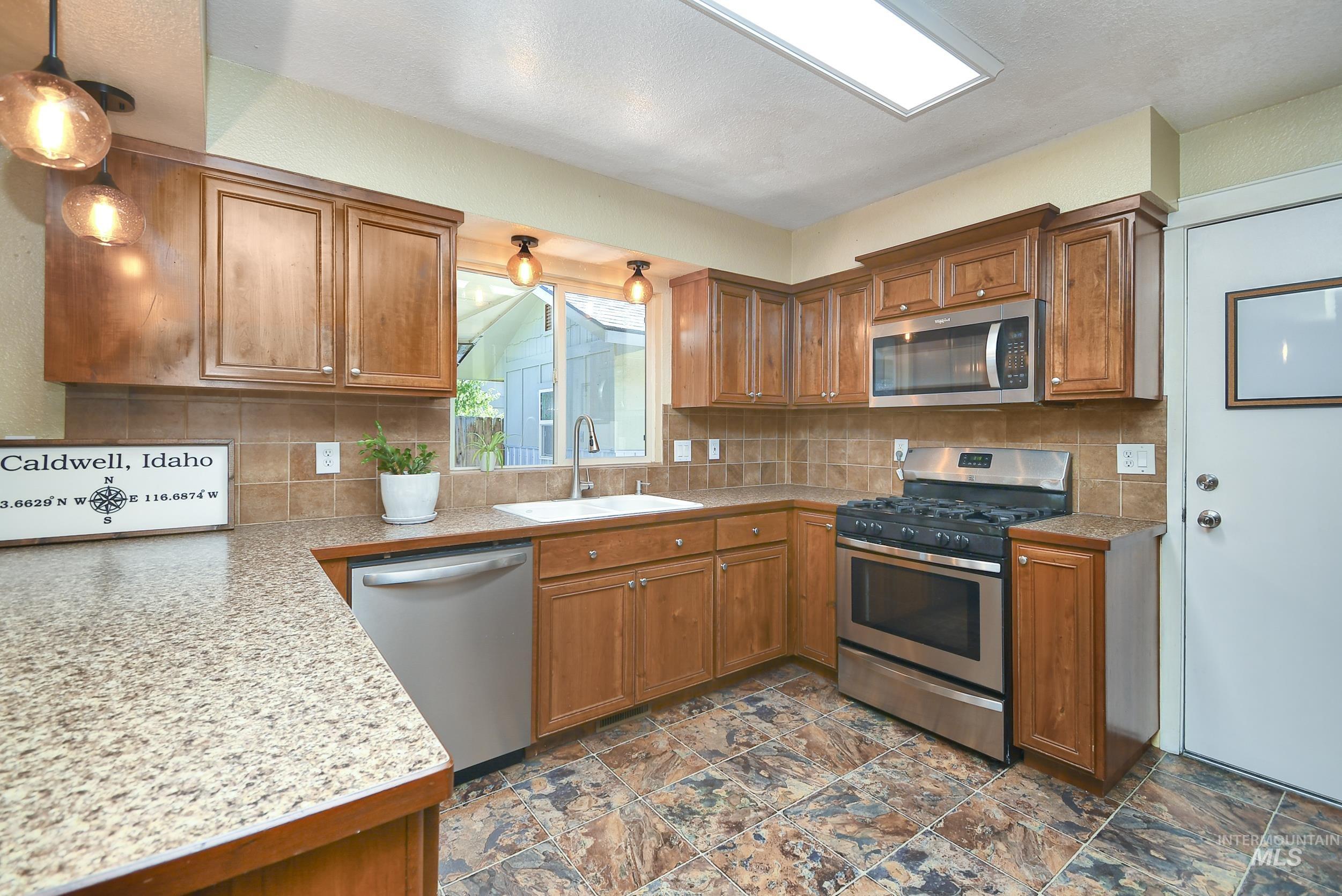 1108 East Ustick Road Caldwell, ID 83607 - Photo 8 of 30 Kitchen featuring wood-finish cabinetry, stainless steel appliances, granite-style countertops, and a tile backsplash