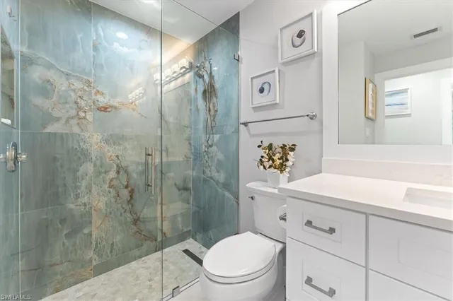 a bathroom with a granite countertop sink a toilet and shower