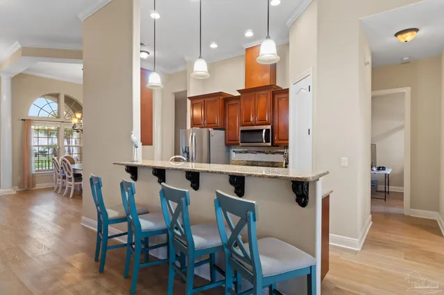a kitchen with stainless steel appliances a dining table chairs and wooden floor