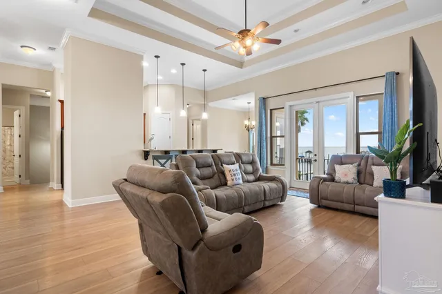 a living room with furniture a ceiling fan a flat screen tv and a large window