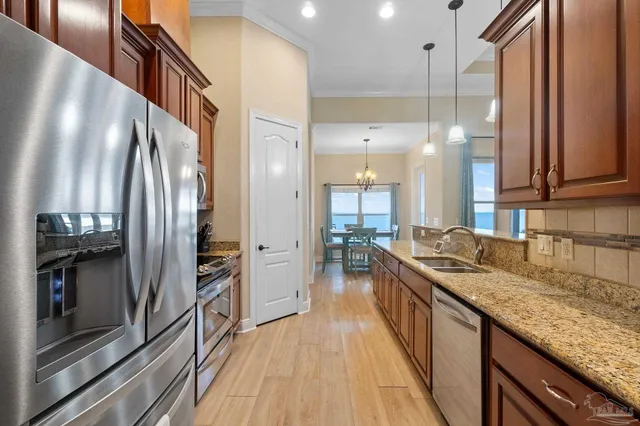 a kitchen with stainless steel appliances granite countertop a refrigerator a stove and a sink