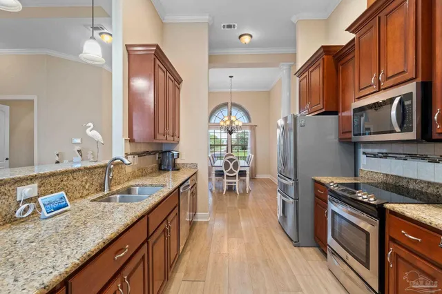 a kitchen with granite countertop a sink a stove refrigerator and cabinets