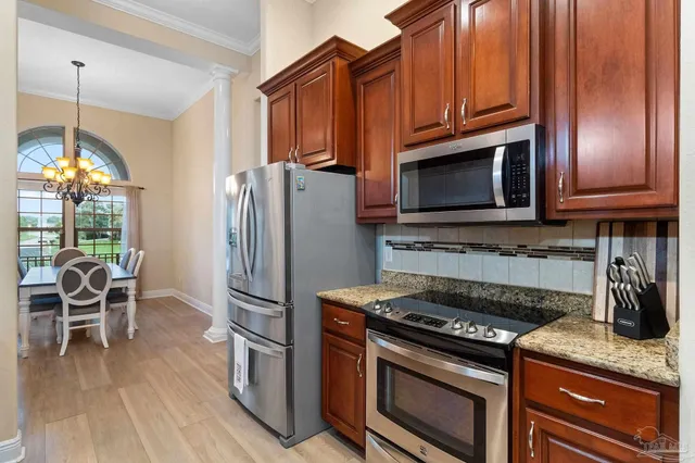 a kitchen with granite countertop wooden cabinets stainless steel appliances and a wooden floor