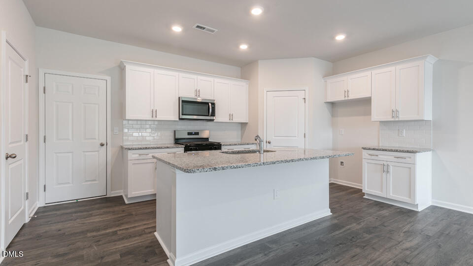 910 Sculptor Street Wendell, NC 27591 - Photo 11 of 44 a kitchen with kitchen island a sink stainless steel appliances and cabinets