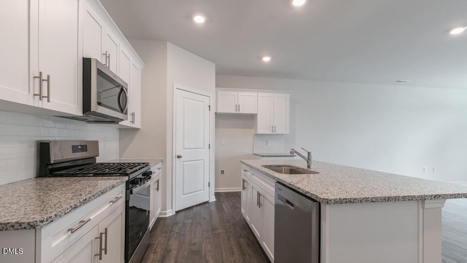 910 Sculptor Street Wendell, NC 27591 - Photo 12 of 44 a kitchen with granite countertop stainless steel appliances a sink stove top oven and cabinets