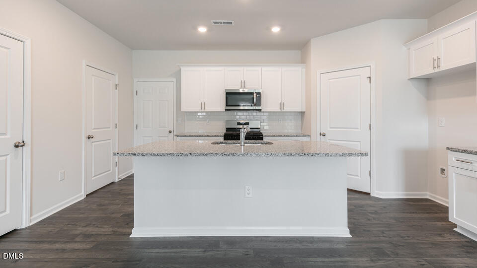 910 Sculptor Street Wendell, NC 27591 - Photo 9 of 44 a kitchen with stainless steel appliances granite countertop a stove a sink and a refrigerator