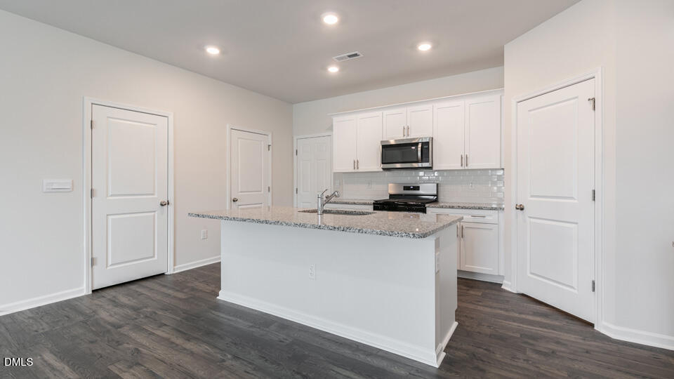 910 Sculptor Street Wendell, NC 27591 - Photo 10 of 44 a kitchen with granite countertop white cabinets and stainless steel appliances