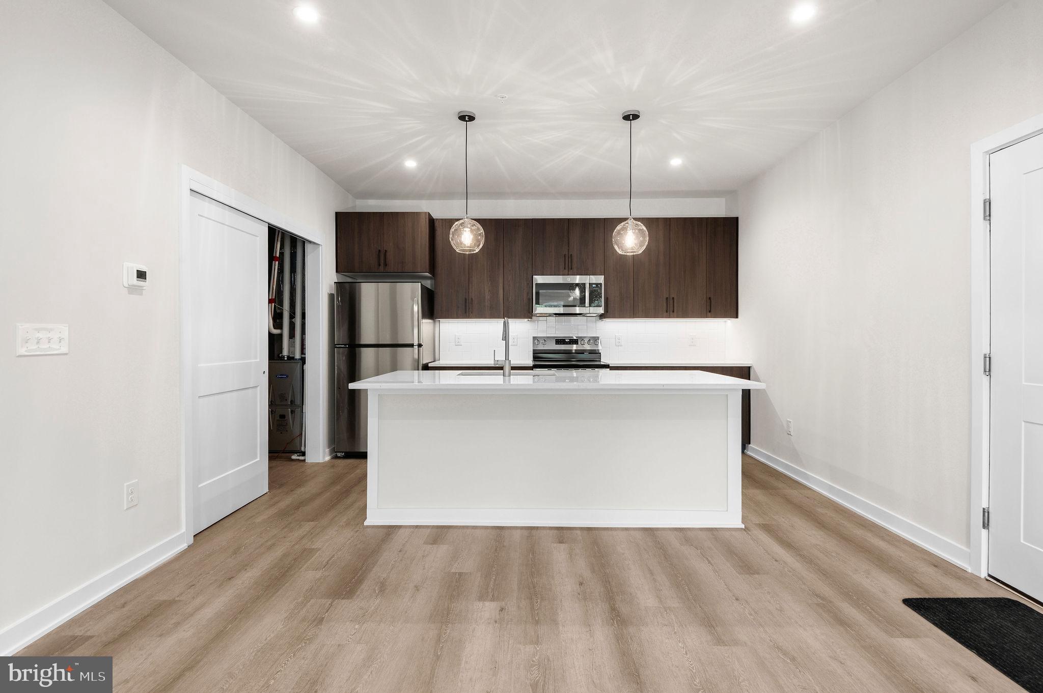 a view of kitchen with kitchen island stainless steel appliances a sink cabinets and wooden floor