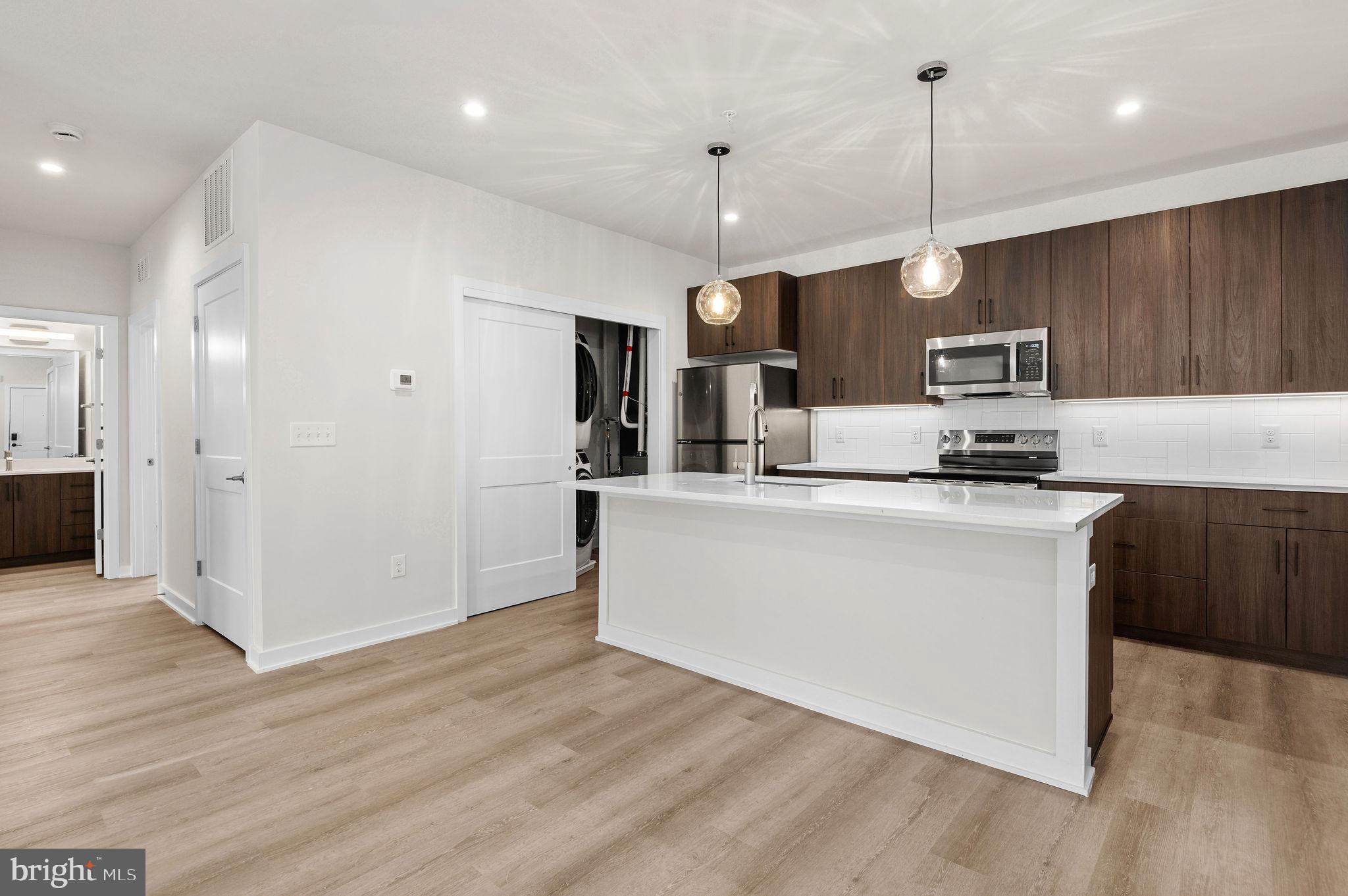 26 South York Road, Unit 402 Hatboro, PA 19040 - Photo 44 of 52 a kitchen with stainless steel appliances granite countertop a refrigerator a stove a sink and a wooden floor