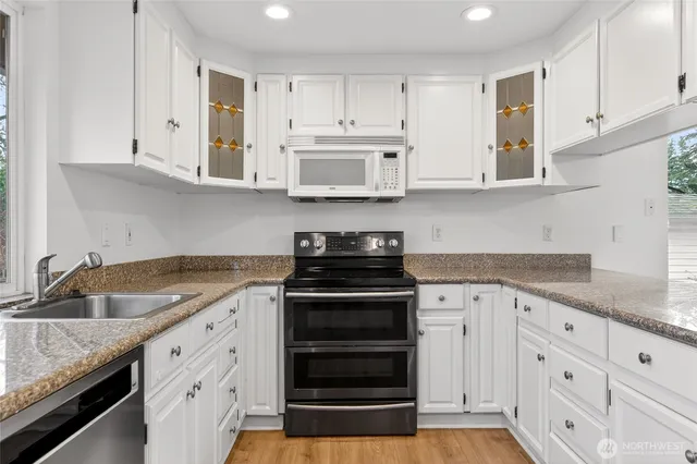 a kitchen with granite countertop white cabinets and stainless steel appliances