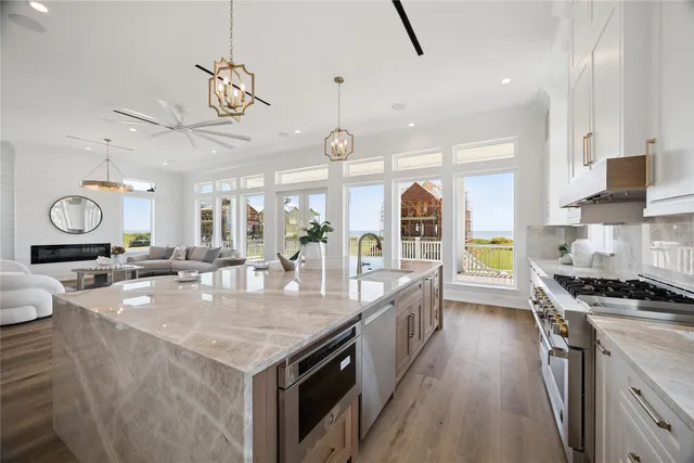 a kitchen with granite countertop a stove a sink a counter space and living room view