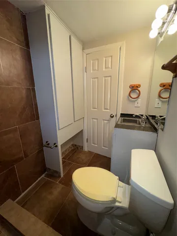 a white toilet sitting next to a bathroom sink and a mirror