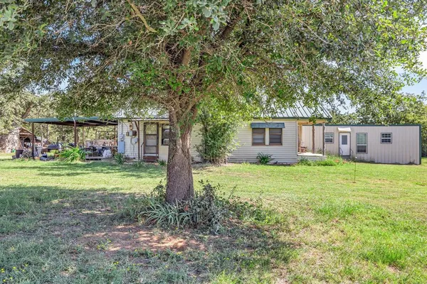 a view of a house with backyard and a tree