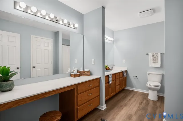 a spacious bathroom with a double vanity sink a toilet and a mirror