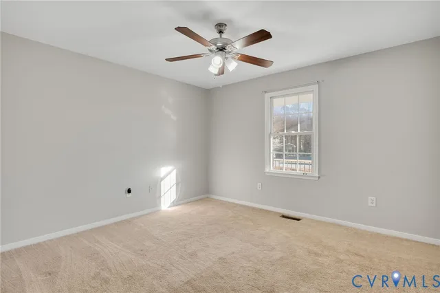 an empty room with ceiling fan and windows