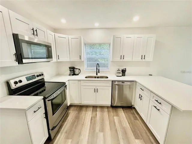 a kitchen with white cabinets sink and stainless steel appliances