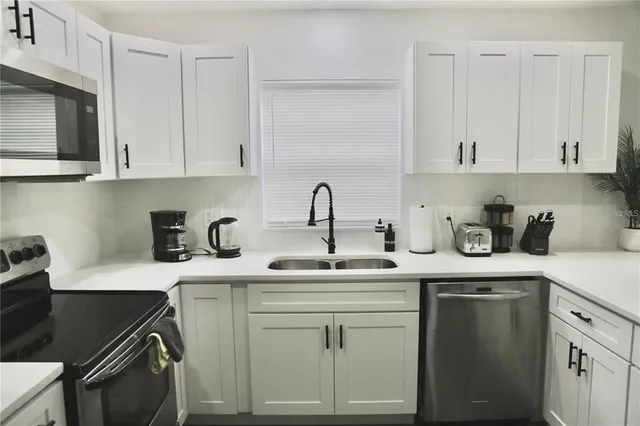 a kitchen with white cabinets a sink and dishwasher